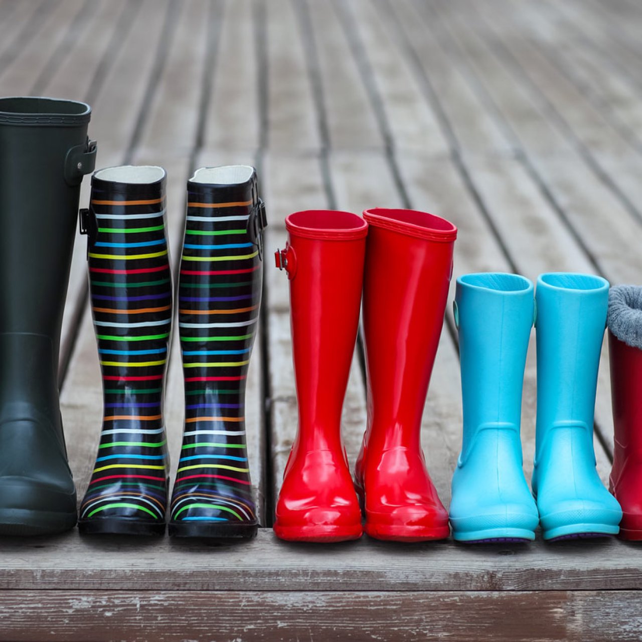 Regenstiefel einer 5-köpfigen Familie stehen auf einem Steg