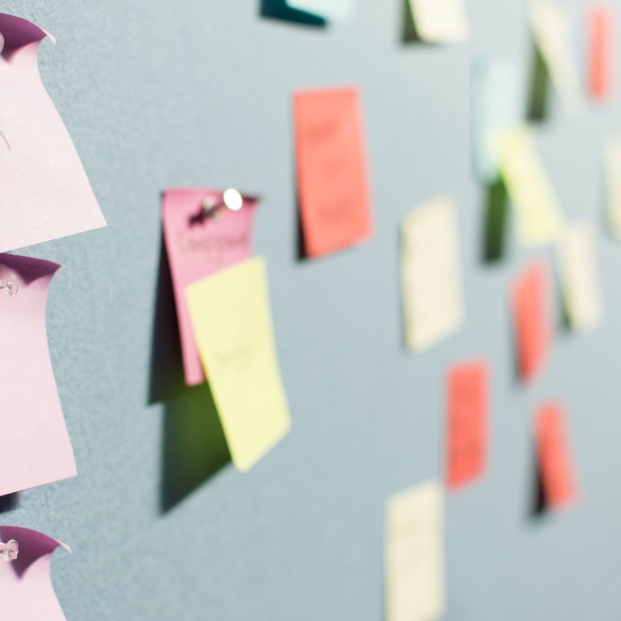 Bild Post-its sind an einer Wand befestigt mit Notizen und Stichwörter drauf.